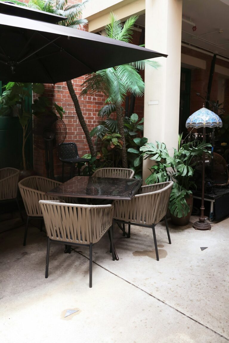 Boho balcony ideas with rattan outdoor seating, layered textiles, terracotta planters, and warm lighting